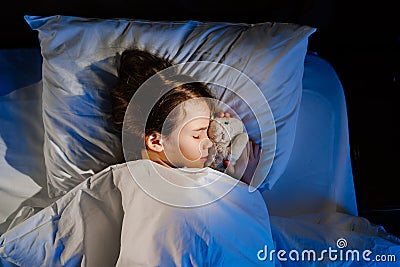 Top view. The pretty teen girl naps with a plush toy, sees a pleasant sleep. Stock Photo