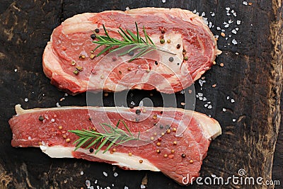 Top view of Raw beef steak with rosemary on wooden dark background, food meat or barbecue Stock Photo