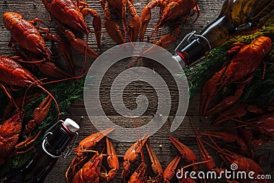 Top view of red lobsters, dill and glass bottles with beer on wooden surface. Stock Photo
