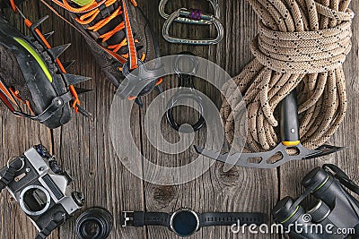 Top view of rock climbing equipment on wooden background. Chalk bag, rope, climbing shoes, belay/rappel device, carabiner and asce Stock Photo