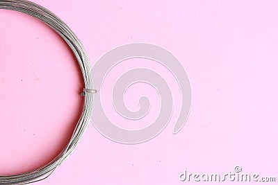 Top view of a roll of a metal wire on a pink background Stock Photo