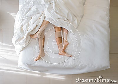 Top view of romantic couple sleeping. bare feet of their legs lying in a bed with white blanket in love and sex concept in modern Stock Photo