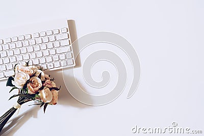 Top view of rose flower on the wireless keyboard on white background. Women`s office desk, female workspace. Valentines ` day Stock Photo