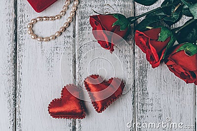 Top view of roses, gift box with bead and two red hearts on wooden background. Stock Photo