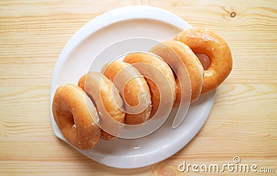 Top View of Rows of Sugar Glazed Doughnuts on White Plate Stock Photo