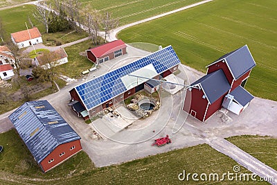 Top view of rural landscape on sunny spring day. Farm with solar photo voltaic panels system on wooden building, barn or house Stock Photo