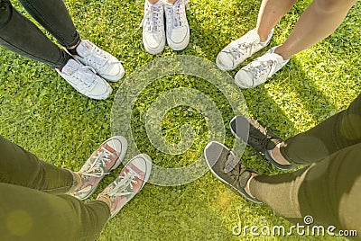 Top view Image of shoes of young teenagers girls standing in a circle on the grass of a park. Enjoying a happy moment and a Stock Photo