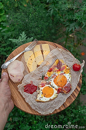 Top view shot of Strammer Max, tomato, cheese, fork and sauce on wooden plate in male hand Stock Photo