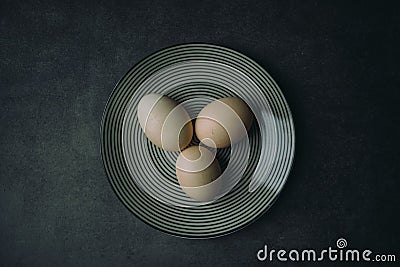 Top view shot of three hard-boiled eggs on a plate on a gray background with copy space Stock Photo