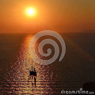 The ship and its shadow in the rays/lights of the setting sun/sunrise, Santorini Greece. Stock Photo