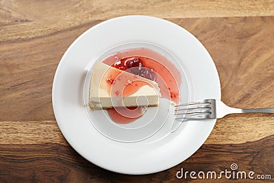 Top view of slice of traditional new york cheesecake with strawberry jam on white plate on wood table Stock Photo