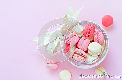 Top view of soft pink, white, and purple mini macaron dessert in glass bowl with handmade white bow Stock Photo