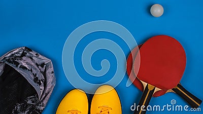 Top view on the sport composition with sneakers, jacket, tennis rocket with ball on the bright blue background, horizontal Stock Photo