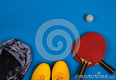 Top view on the sport composition with sneakers, jacket, tennis rocket with ball on the bright blue background Stock Photo