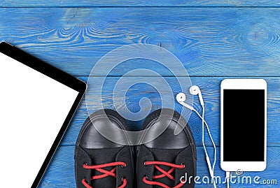 Top view of sports shoes by tablet computer and mobile phone with screen and in-ear headphones and white empty blank Stock Photo