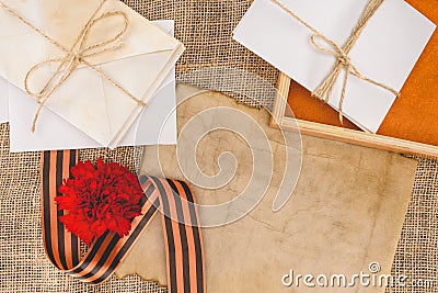 top view of st. george ribbon, carnation, old empty paper, pile of letters and photo frame Stock Photo