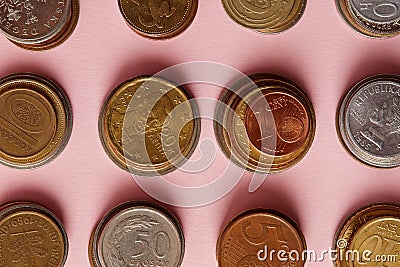 top view of stacks of coins from various countries on pink Stock Photo