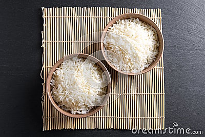 Top view: steamed cooked basmati rice in round ceramic bowls over black stone Stock Photo