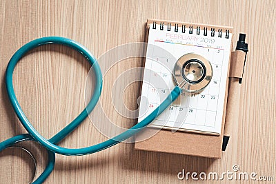 Top view of stethoscope on calendar for health checkup concept., Annual doctor appointment for physical check-up against wooden Stock Photo