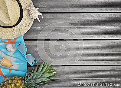 straw hat, beach towel, sunglasses and pineapple on wooden terrace Stock Photo