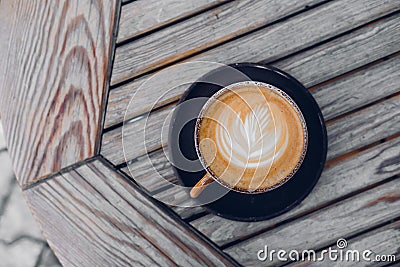 Top view on stylish latte coffee mug with flower art on wooden table background Stock Photo
