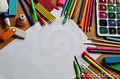 Top view on table with blank sheet of paper. Back to school concept with space for text. Color paints with paint brushes, pencils Stock Photo