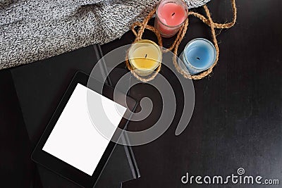 Top view of tablet with blank screen on top of notebook with three colourful candles. Stock Photo