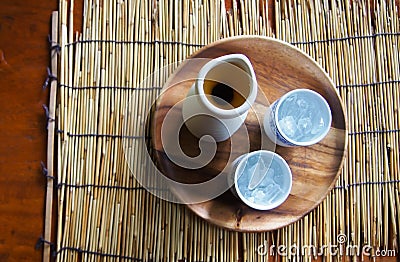 Top view of tea pot and glass of iced tea. On a wooden plate, which is placed on a bamboo mat and on a table Stock Photo