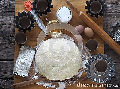 Top view.Test for Easter cakes, croissants, rolls on the background of molds for Easter cakes and ingredients for kneading dough Stock Photo