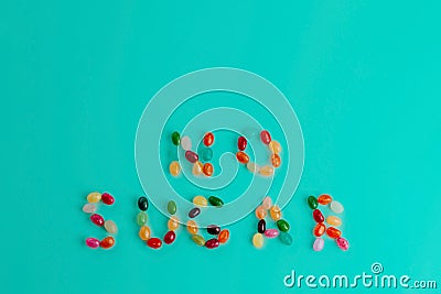 Top view of text made of colorful bean sweet candies on turquoise blue background. Healthy food and diet concept. Copy Stock Photo