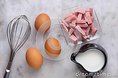 Top view of three raw brown egg, flour, milk and cutted sausages as ingredients of omelette on the marble surface Stock Photo