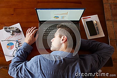 Top view of tired exhausted businessman sleeping on laptop keyboard at workplace. Handsome overworked freelancer man Stock Photo