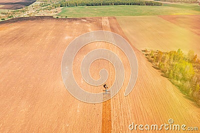 Top View Tractor Plowing Field In Spring Season. Beginning Of Agricultural Spring Season. Cultivator Pulled By A Tractor Stock Photo