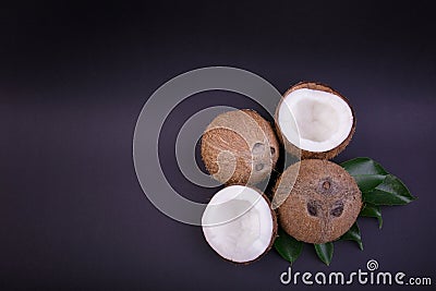 Top view of tropical coconuts with green leaves. Organic and nutritious nuts. Whole and cut coconuts with leaves, close-up. Stock Photo