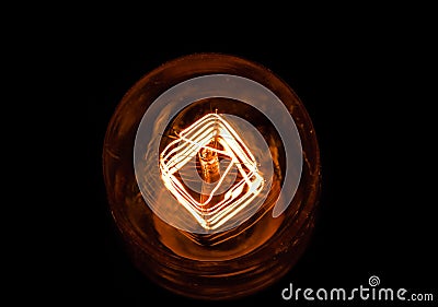 Top of view of turn on in slow motion with dust, retro vintage light bulb with old technology with filament built-in with warm Stock Photo