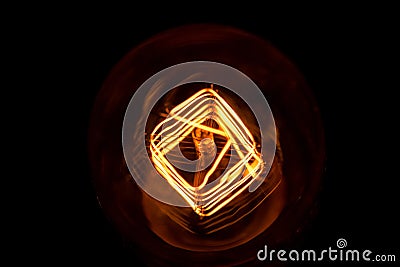 Top of view of turn on in slow motion with dust, retro vintage light bulb with old technology with filament built-in with warm Stock Photo