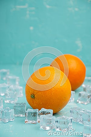 Top view of two oranges with ice on table and blue background, vertical, Stock Photo