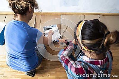 Top view. Two women loading paint roller in paint tray. Preparing to paint house walls white Stock Photo