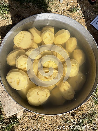 Top view of uncooked peeled potatoes in a pan with water; funny faces curved on potatoes Stock Photo