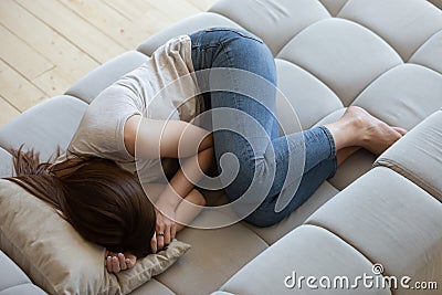 Top view unhappy depressed young woman lying on couch Stock Photo