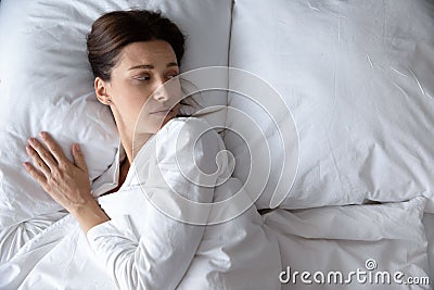 Top view unhappy young woman lying in bed alone Stock Photo