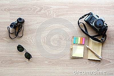 Top view vintage camera, sunglasses, binoculars and notepad with pen on the wooden background with copy space for adding some text Stock Photo