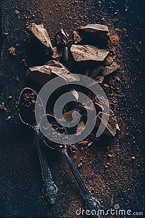 top view of vintage spoons, chocolate pieces and cocoa powder on dark surface Stock Photo