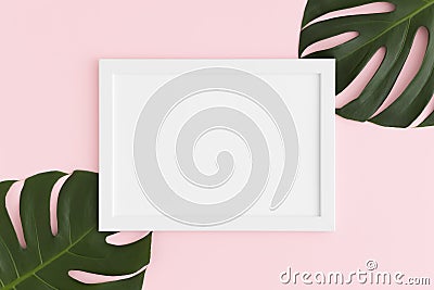 Top view of a white frame mockup with monstera leaf decoration on a pink background. Landscape orientation Stock Photo