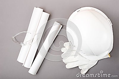 Top view white helmet, gloves, plan, drawings, construction glasses on grey background, workplace, plans of architect, builder Stock Photo