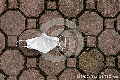 Top view of a white KN95 mask littered on a sidewalk. Backside of face mask Stock Photo