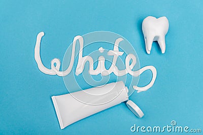 Top view of white lettering near tube of toothpaste and tooth model on blue background. Stock Photo