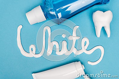 Top view of white lettering from toothpaste, tooth model and mouthwash on blue background. Stock Photo