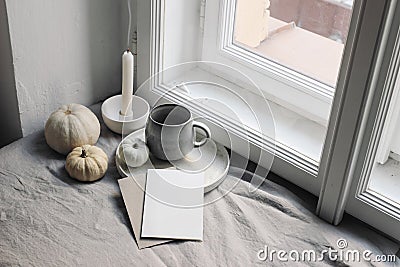 Top view of white little pumpkins, cup of coffee and smoking candle near window. Blank greeting card mockup. Autumn Stock Photo