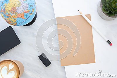 Top view of white pencil on brown paper with blue globe,blackboard,coffee cup and plant on marble table.new yearâ€™s resolutions Stock Photo